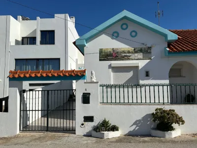 Een charmant wit huis met blauwe accenten en een rood dak in Torres Vedras op een zonnige dag.