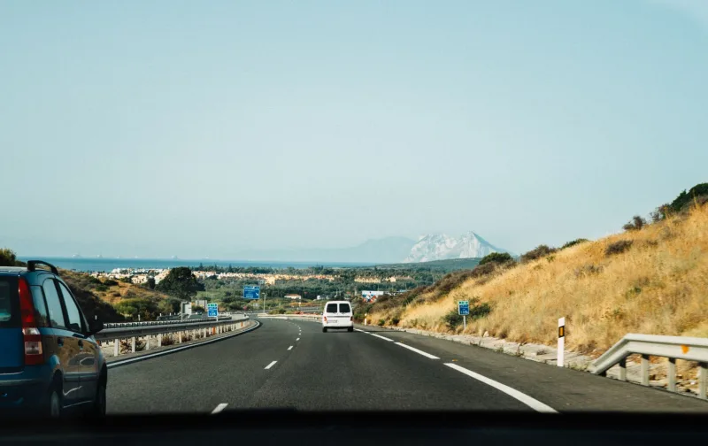 Uitzicht vanuit een auto op een Spaanse snelweg, met op de achtergrond bergen en een schilderachtig landschap.