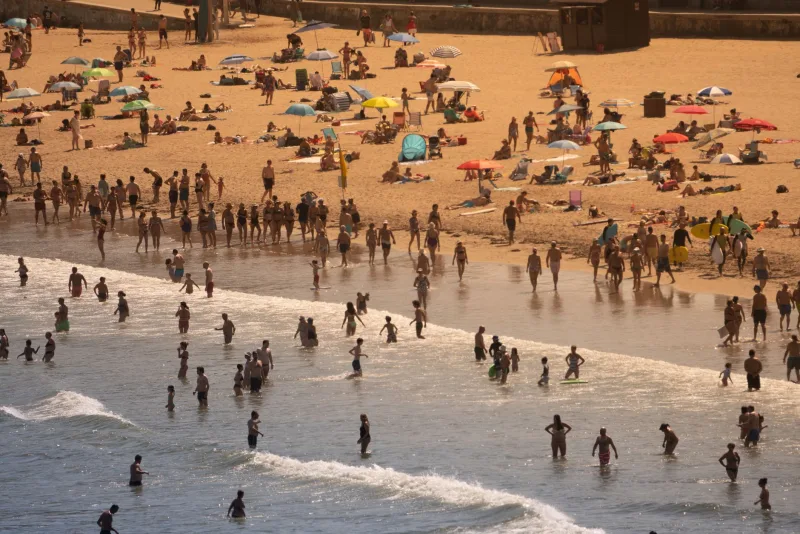 Luchtview van een druk strand met mensen die genieten van een zonnige zomerdag.