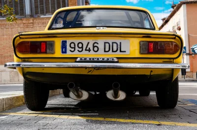 Achteraanzicht van een klassieke gele Triumph auto geparkeerd op straat in Aranjuez, Spanje.