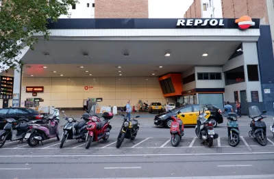 Repsol-tankstation in Barcelona, met geparkeerde scooters en taxi's.