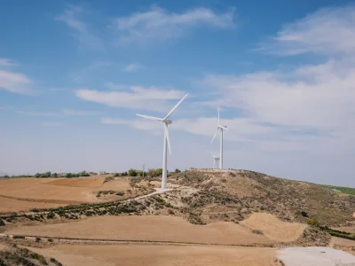 Windturbines die hernieuwbare energie genereren in een landelijk landschap onder een heldere blauwe lucht.