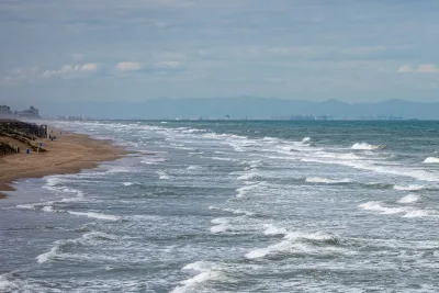 Schilderachtig uitzicht op het strand van Valencia, met golven die op de zandige kust breken onder een bewolkte hemel.